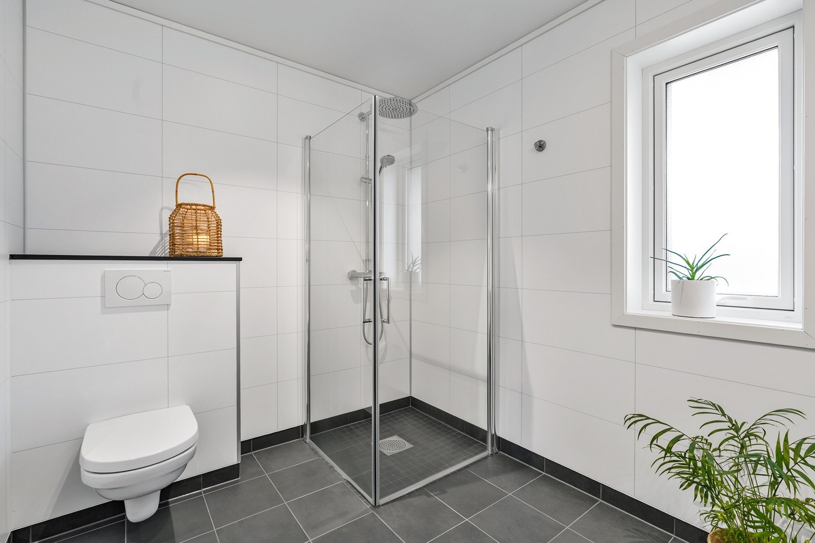 Badet er innredet med baderomsinnredning med servant, vegghengt skap, vegghengt toalett og dusjhjørne. Galleribilde