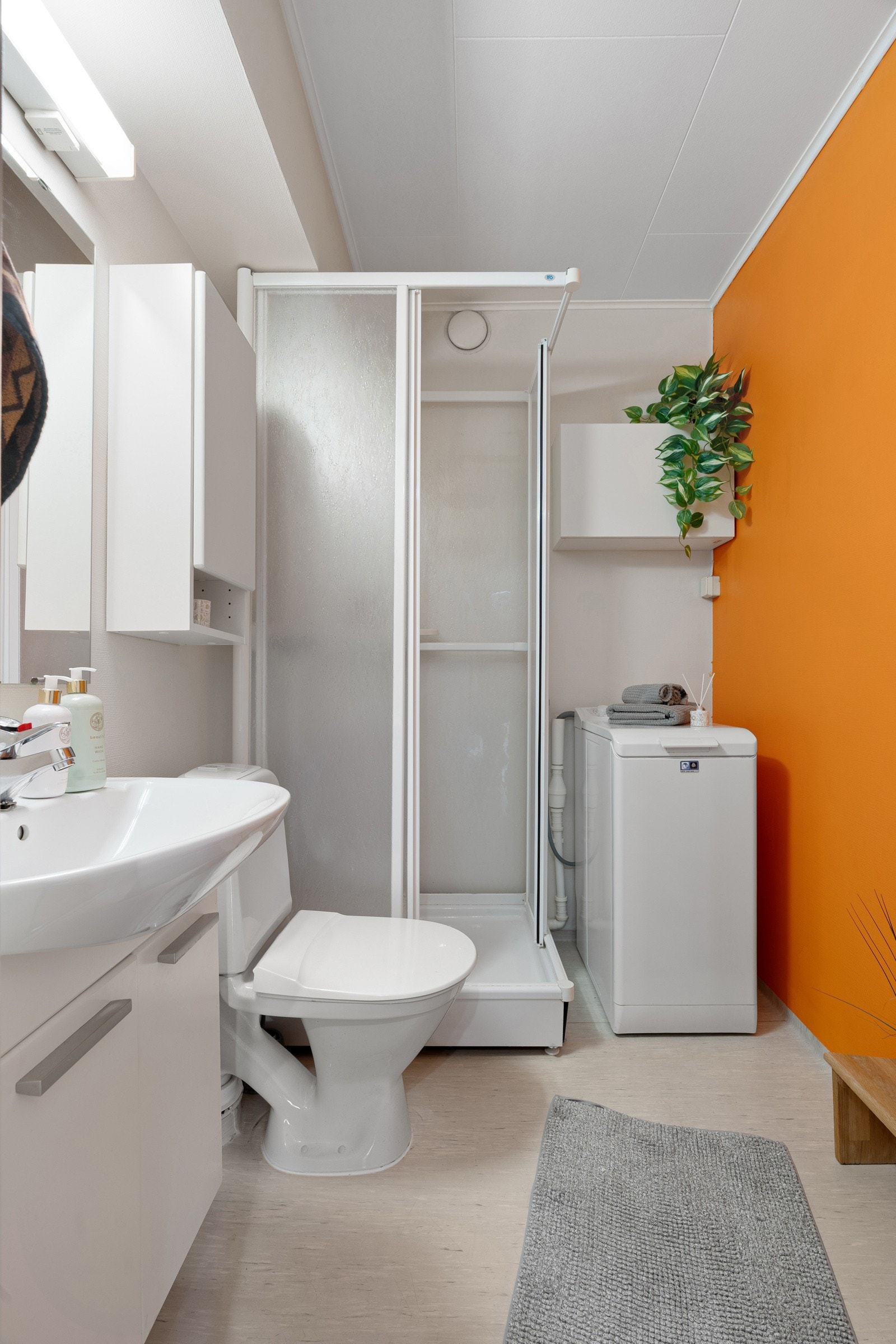 Baderommet er praktisk utformet med dusjkabinett, servant med oppbevaringsplass og opplegg til vaskemaskin.