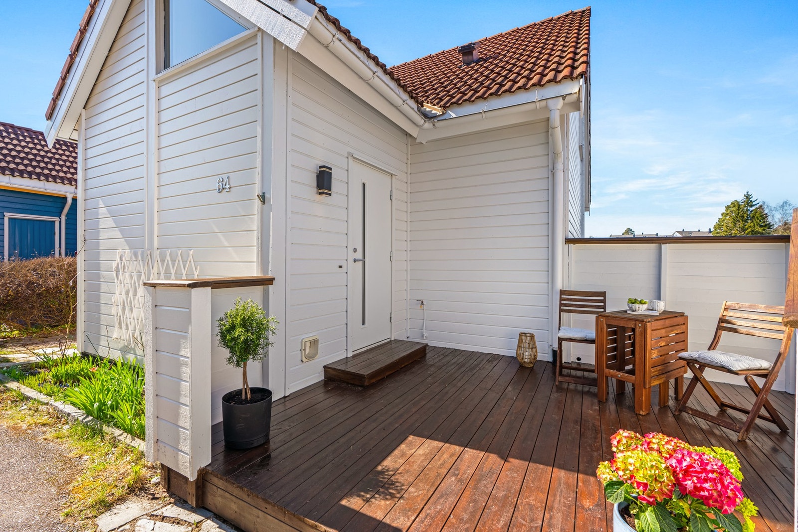 Inngangsparti med terrasse, hvitmalt fasade og rødt tak. Galleribilde