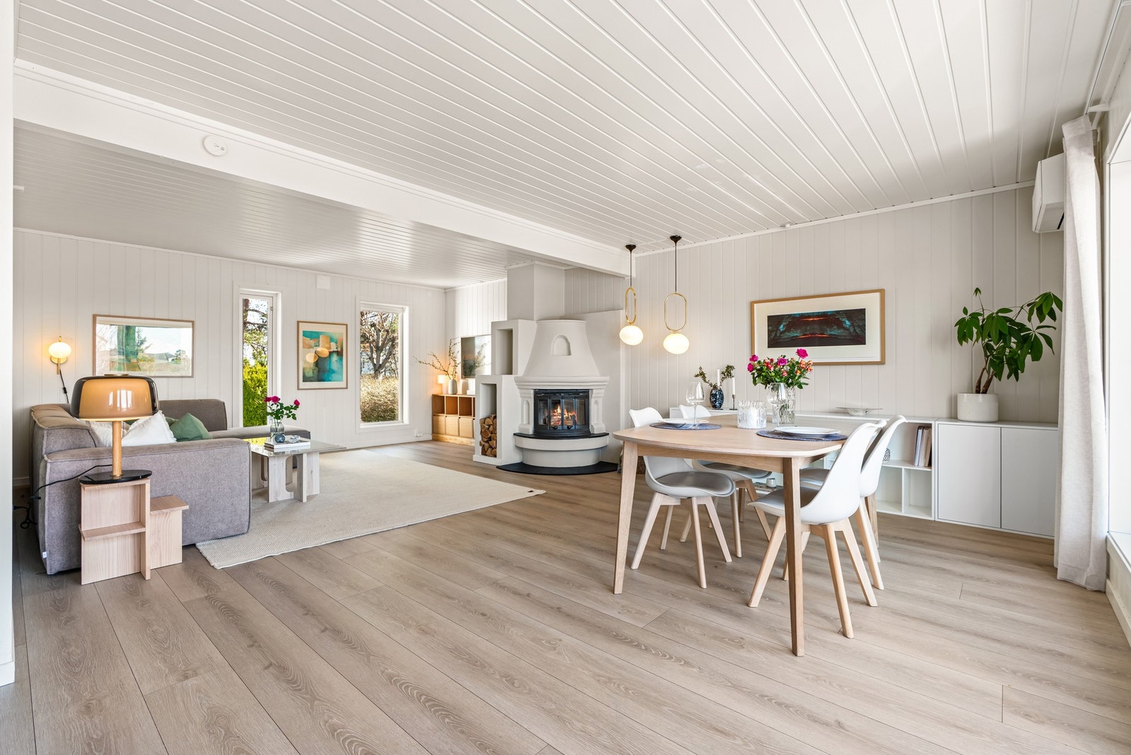 Romslig stue med peis, store vinduer og lys parkett. Galleribilde