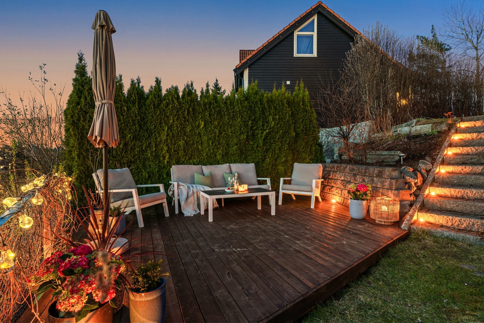Uteområde med terrasse, trapp med belysning og hekk som skaper en skjermet atmosfære. Galleribilde