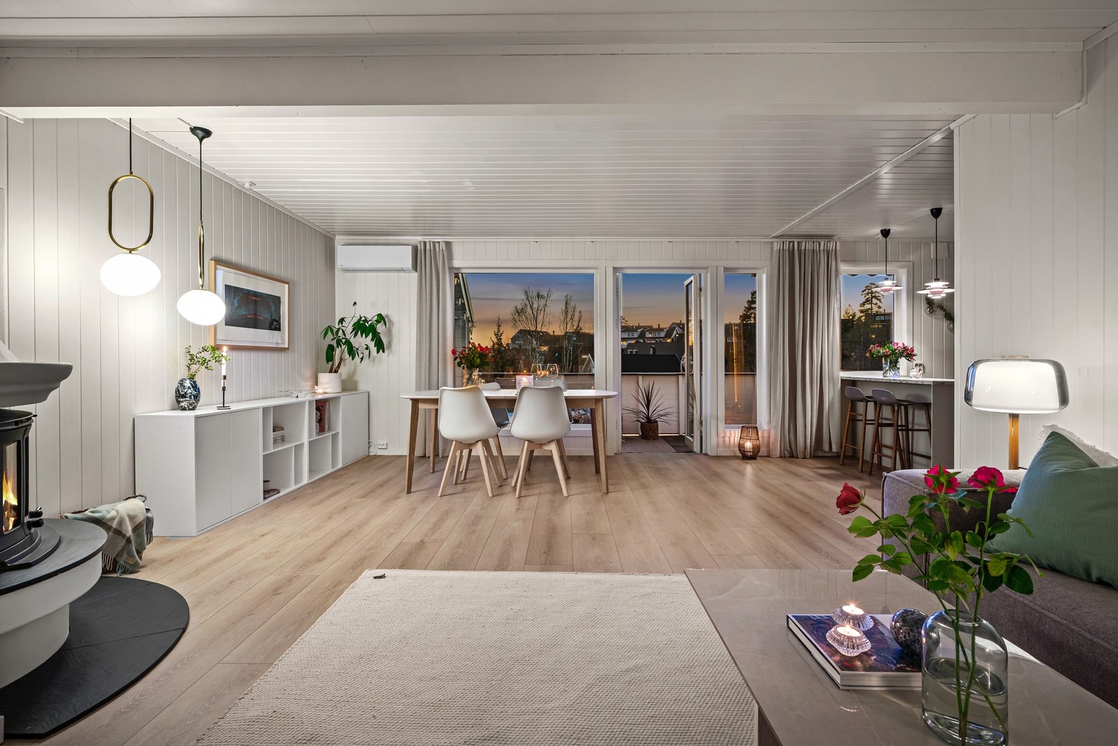 Åpen stue med store vinduer og utgang til balkong. Lyse vegger og tak, samt parkettgulv. Galleribilde