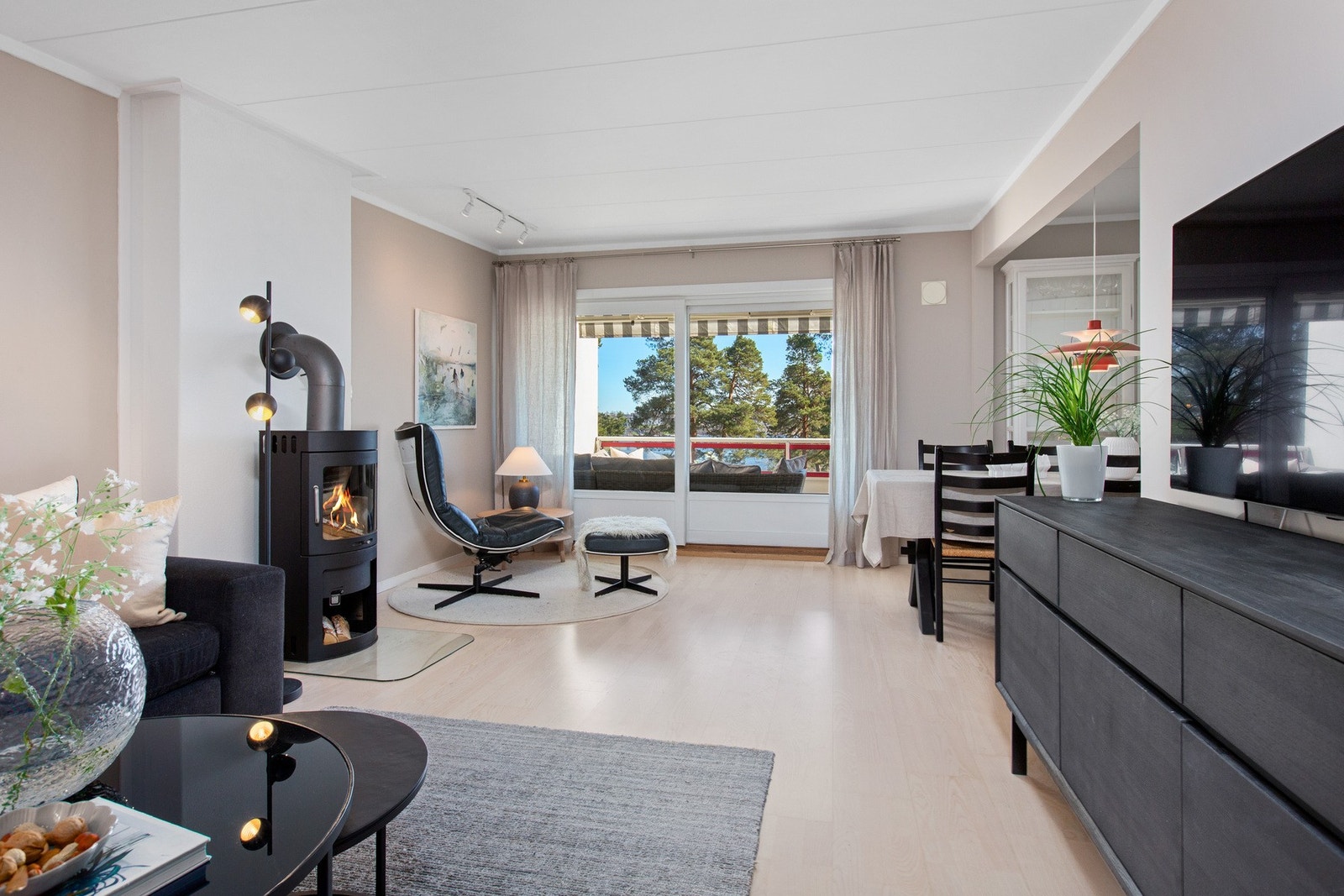 En moderne peisovn er plassert sentralt i rommet og kan nytes fra flere vinkler, også fra kjøkkenet. Galleribilde
