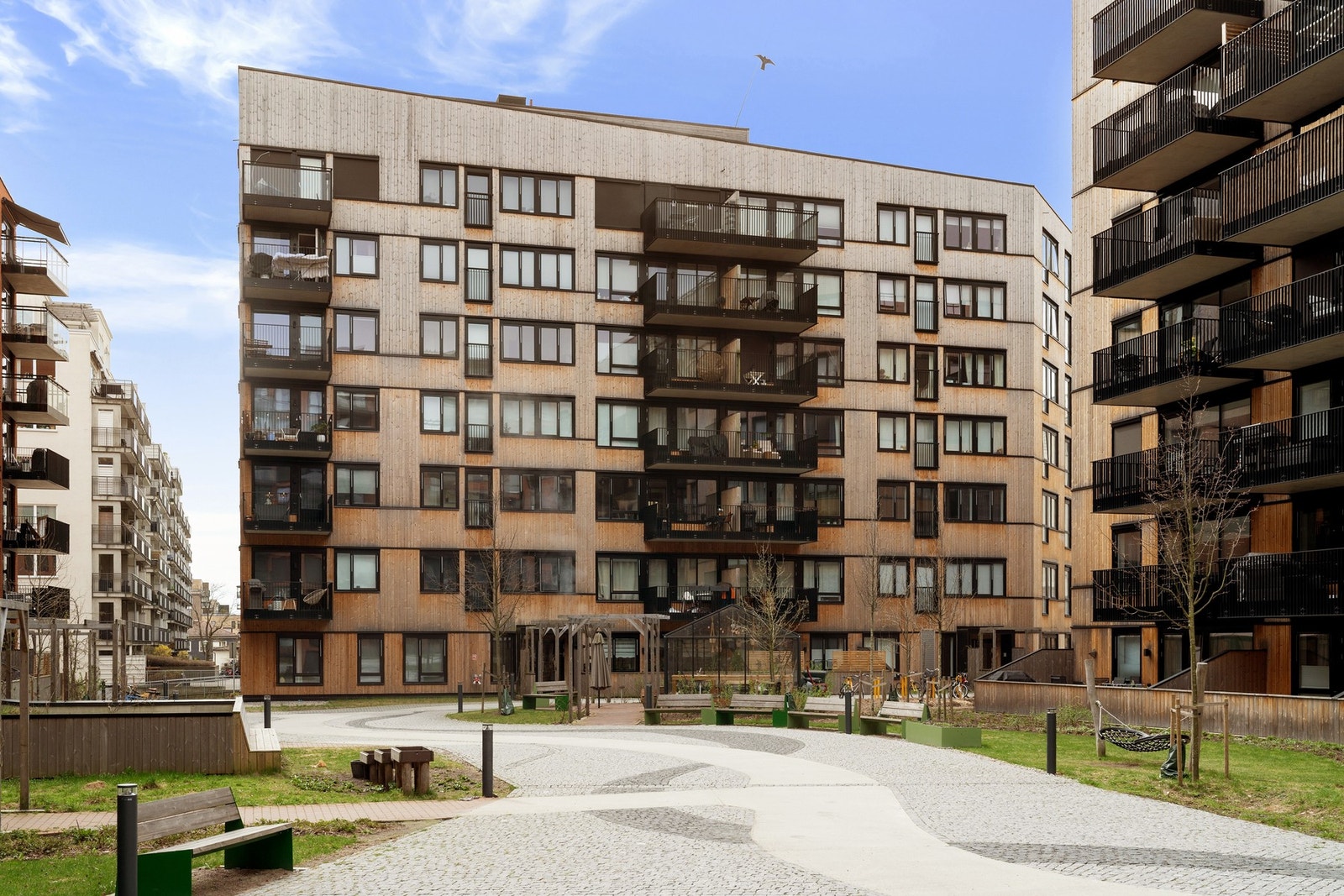 Bakgården er pent opparbeidet med asfalterte veier, gressplen, og sittebenker. Galleribilde