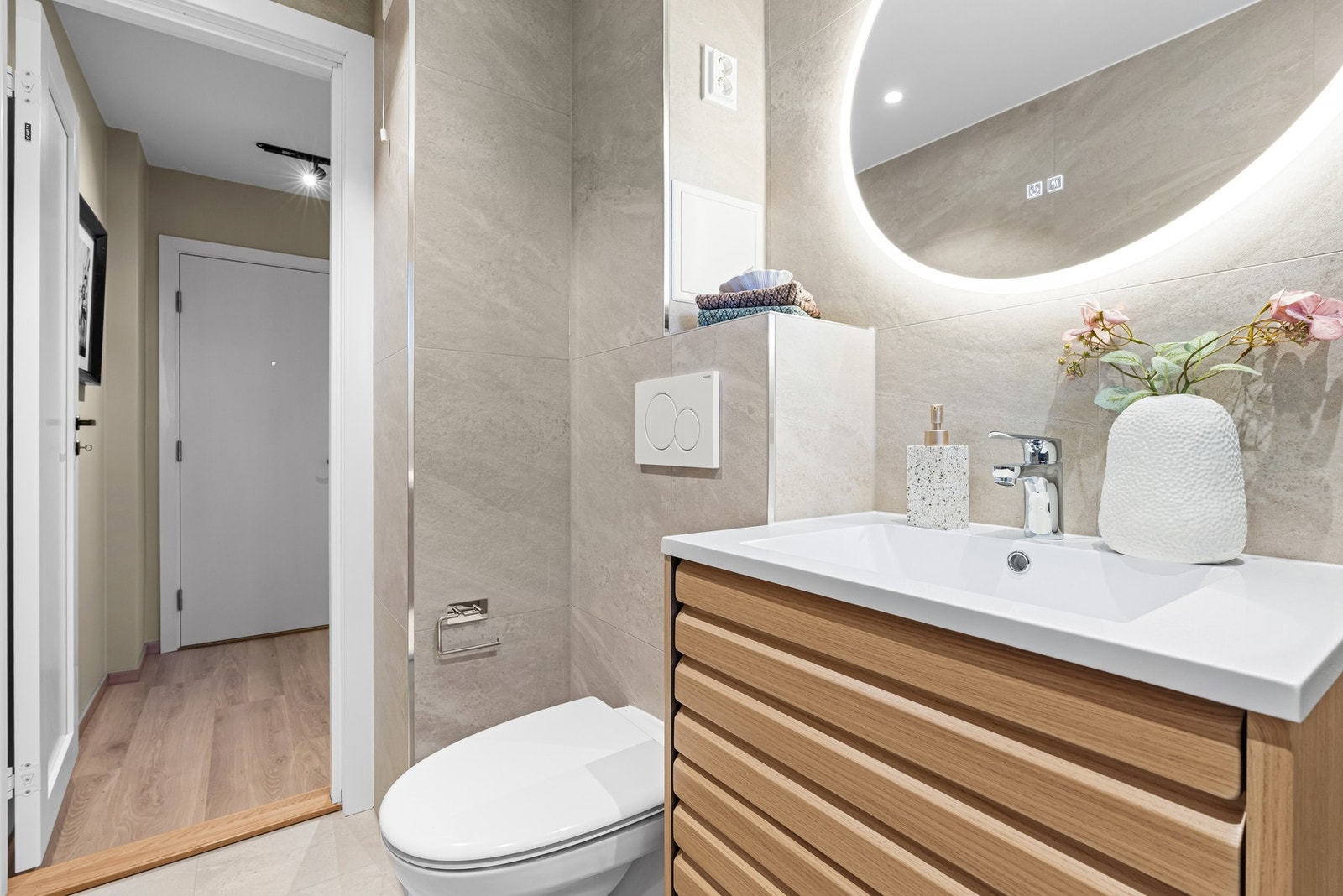 Baderom med moderne innredning, speil med integrert belysning og flislagte vegger. Galleribilde