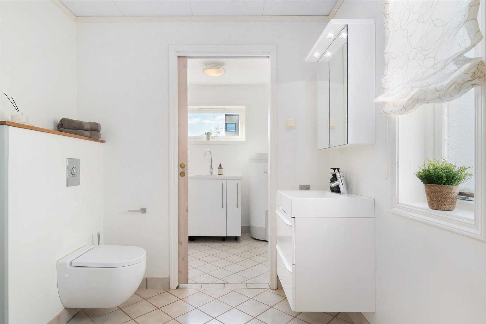 Badet i første etasje har skyvedør inn til vaskerom. Her er fliser på gulvet og malt strie og flis på veggene. Skuffeinnredning med servant, speilskap, vegghengt toalett - Galleribilde