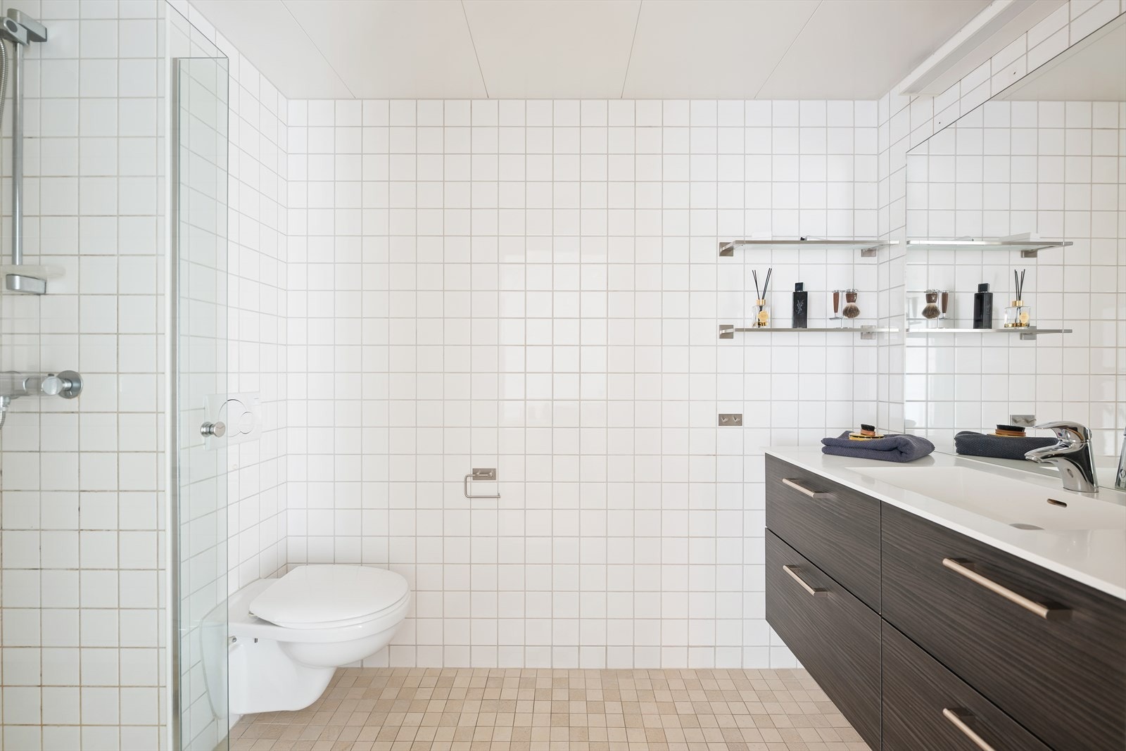 Pent og romslig bad med flislagte overflater, gulv med termostatstyrte varmekabler og downlights i himlingen. Galleribilde