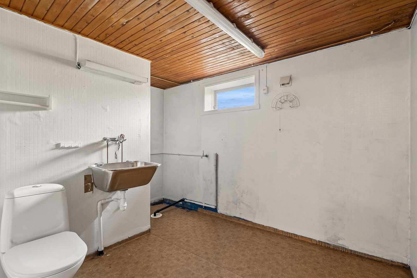Vaskerommet har vinylbelegg på gulv og vegg, og er utstyrt med utslagsvask og gulvmontert WC. Galleribilde