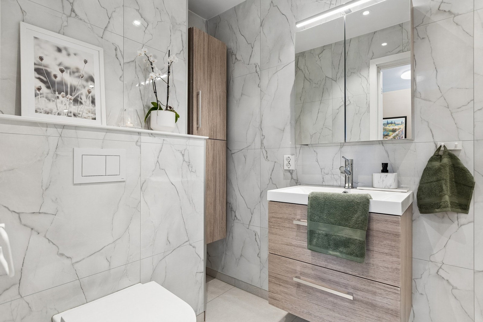 Badet fremstår som moderne og delikat etter totalrenovering i 2025, og er utstyrt med behagelig gulvvarme, vegghengt servant med tilhørende møbel, samt speilskap med integrert belysning og stikkontakt. Galleribilde