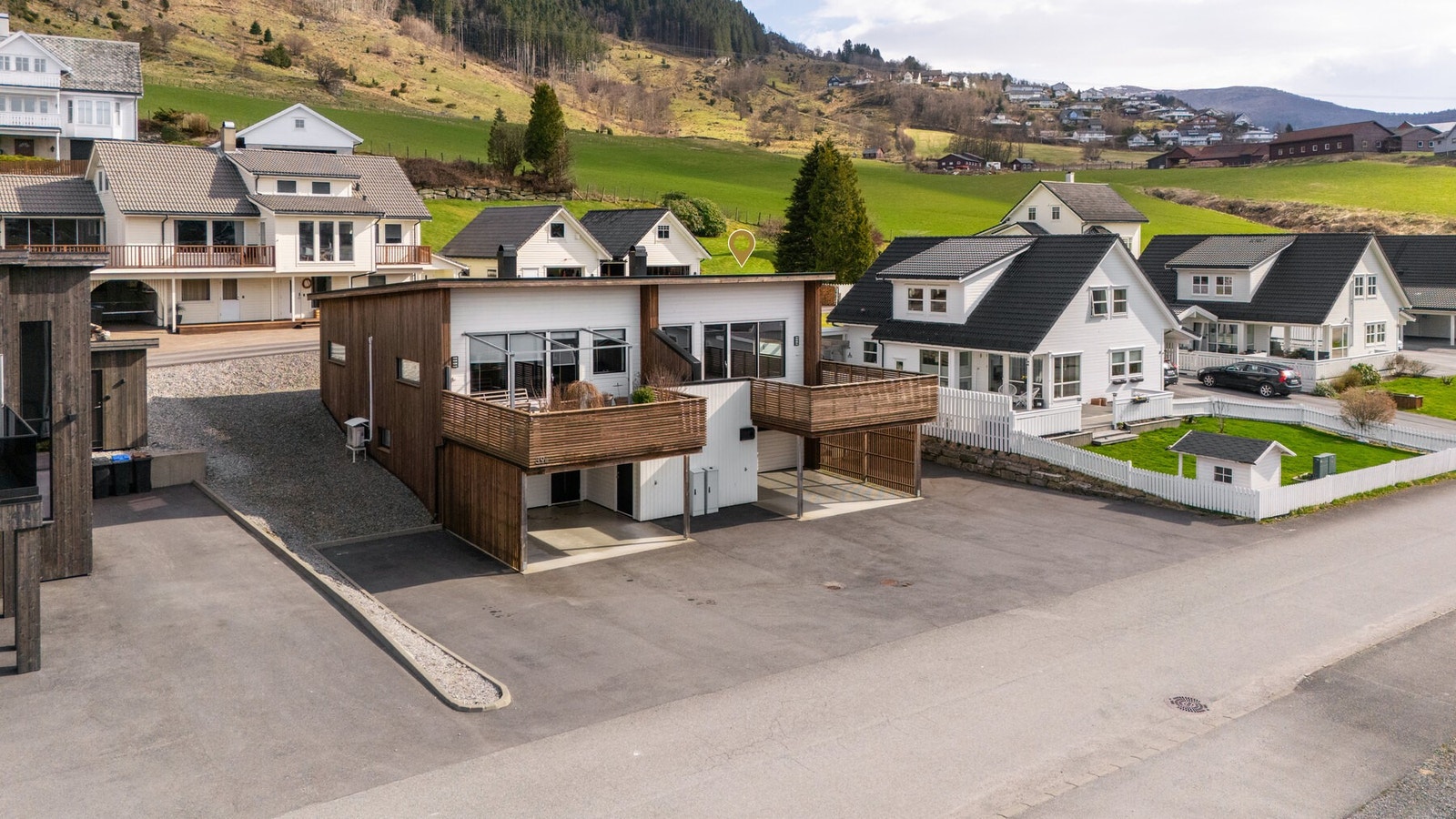 Bygningen er en moderne tomannsbolig i to etasjer, med fasade av tre og store vindusflater. Galleribilde
