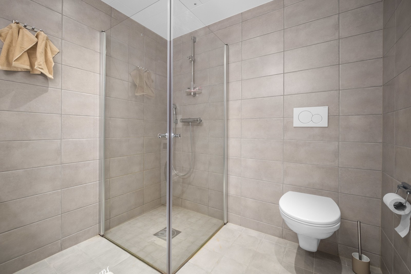 Badet er utstyrt med servant på benkeskap, speil, belysning, vegghengt toalett og dusj med innfellbare dører i herdet glass Galleribilde