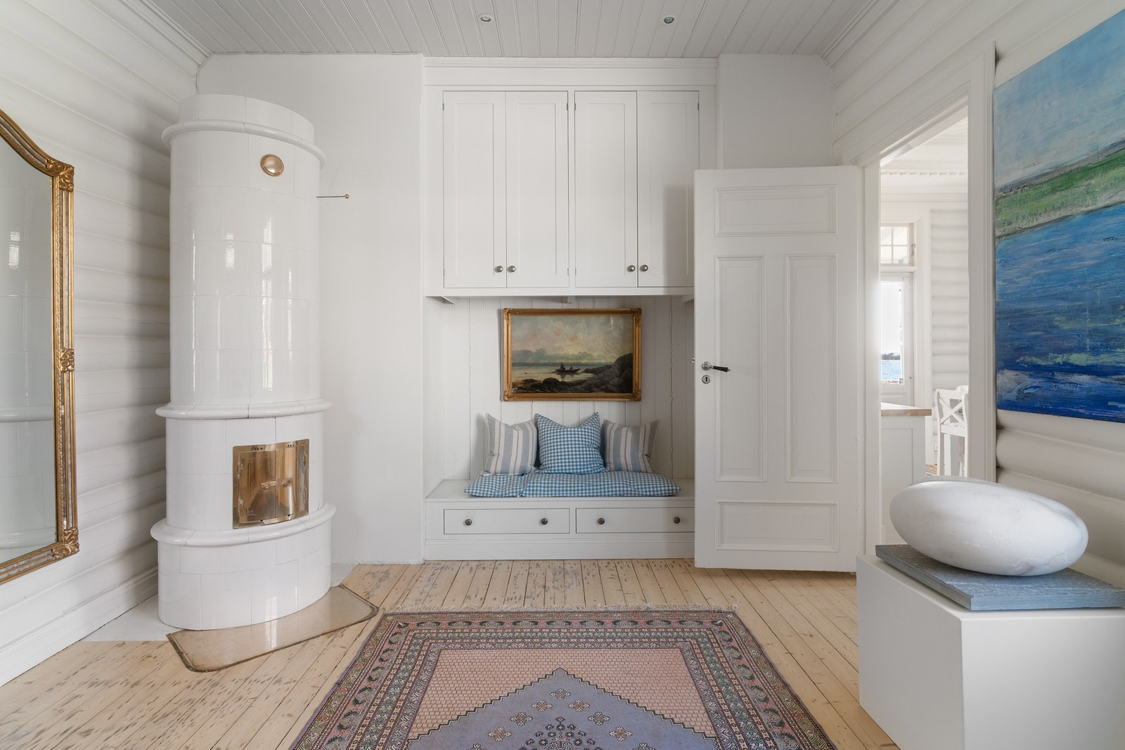 Gangen gir et godt førsteinntrykk når man kommer inn i boligen, med en kakkelovn som skaper en varm og innbydende atmosfære. Innebygget skap og sittebenk fra Kvänum. Galleribilde