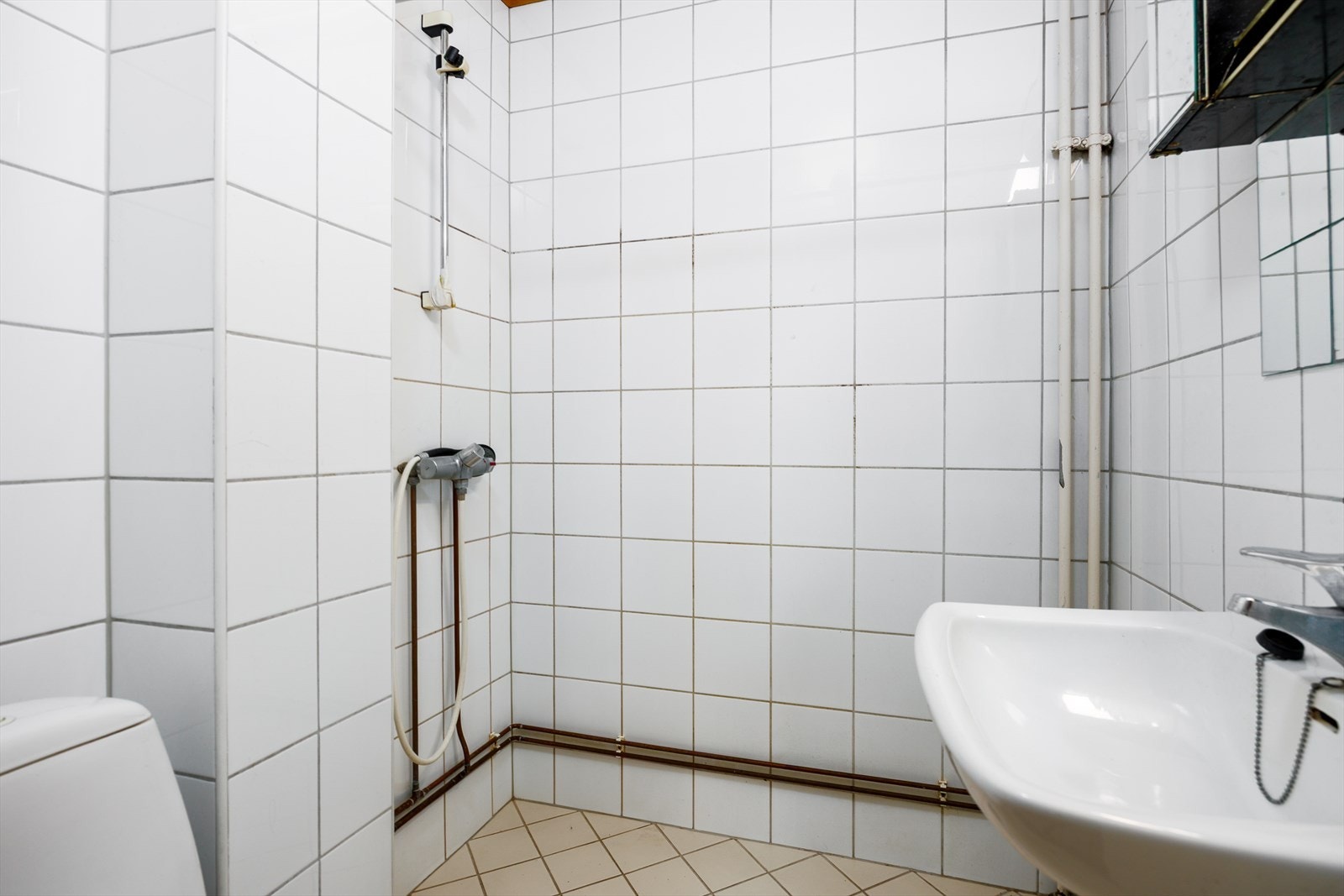 Badet er flislagt og har dusjsone med vegger i hjørneløsning Galleribilde