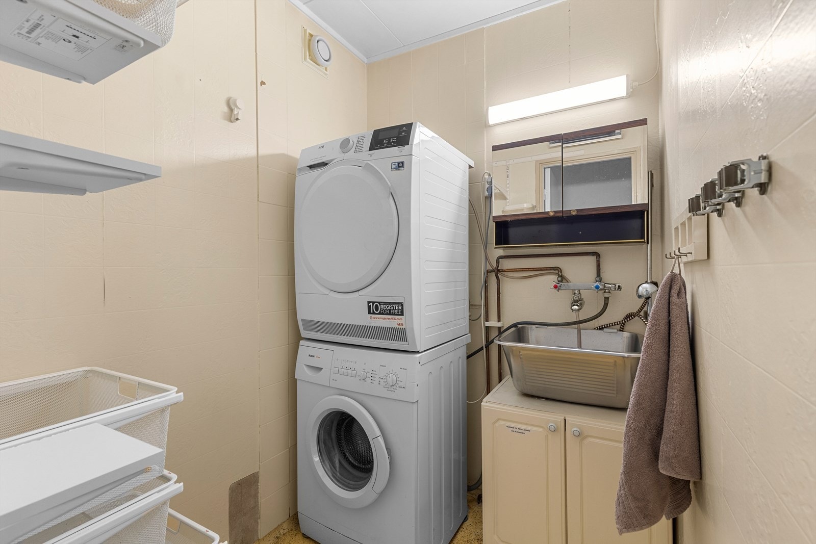 Vaskerommet har utslagsvask, opplegg for vaskemaskin og plass til oppbevaring. Galleribilde