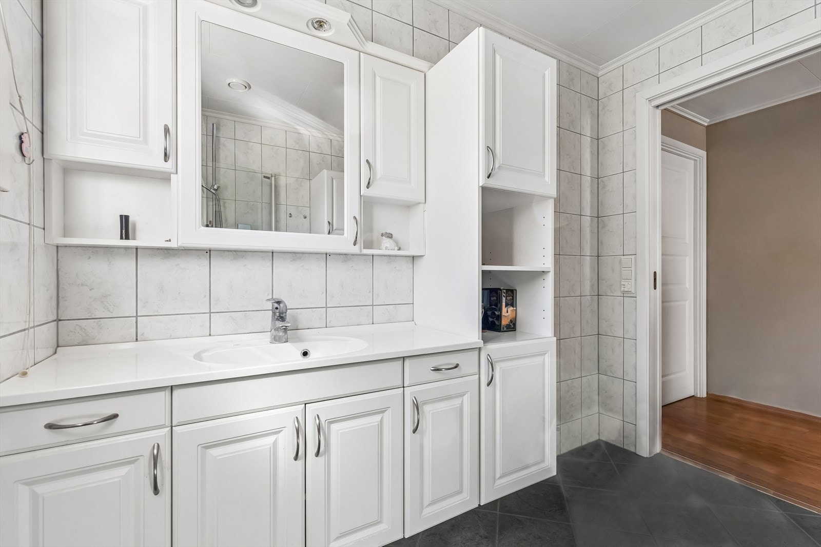 Badet er flislagt og utstyrt med en stor baderomsinnredning med heldekkende servant og speil. Galleribilde