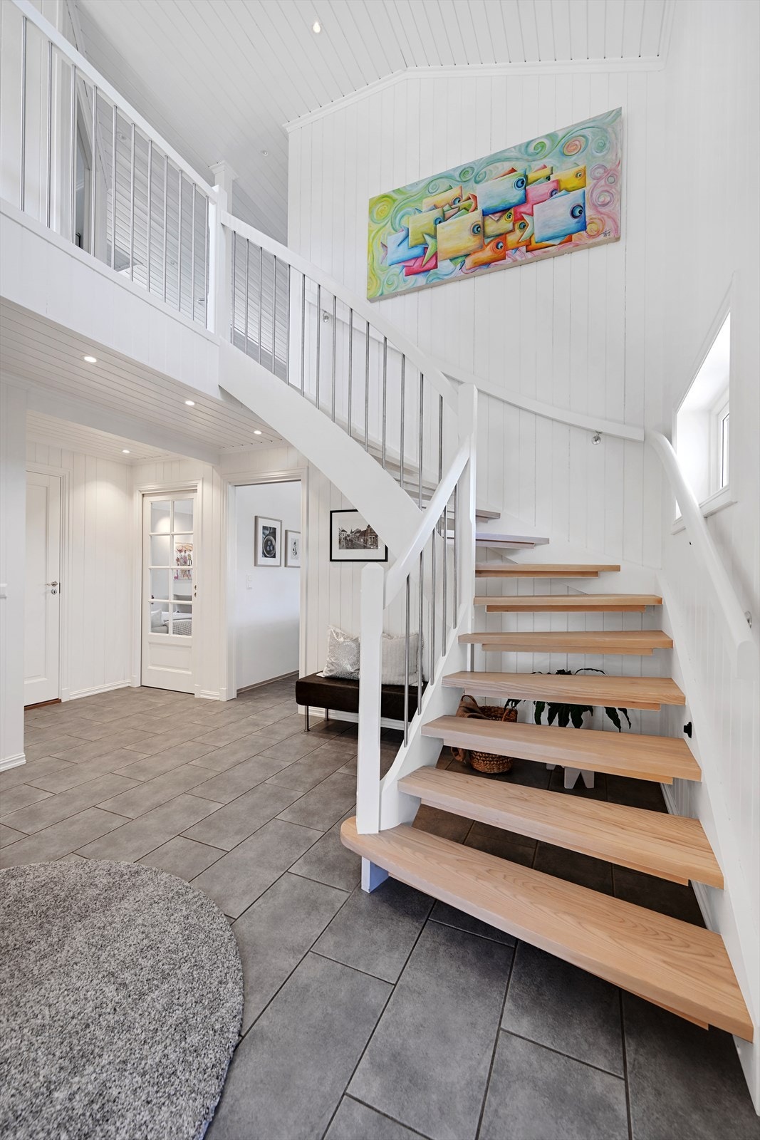 Den malte tretrappen med trinn i lakkert ask binder de to etasjene elegant sammen. Galleribilde