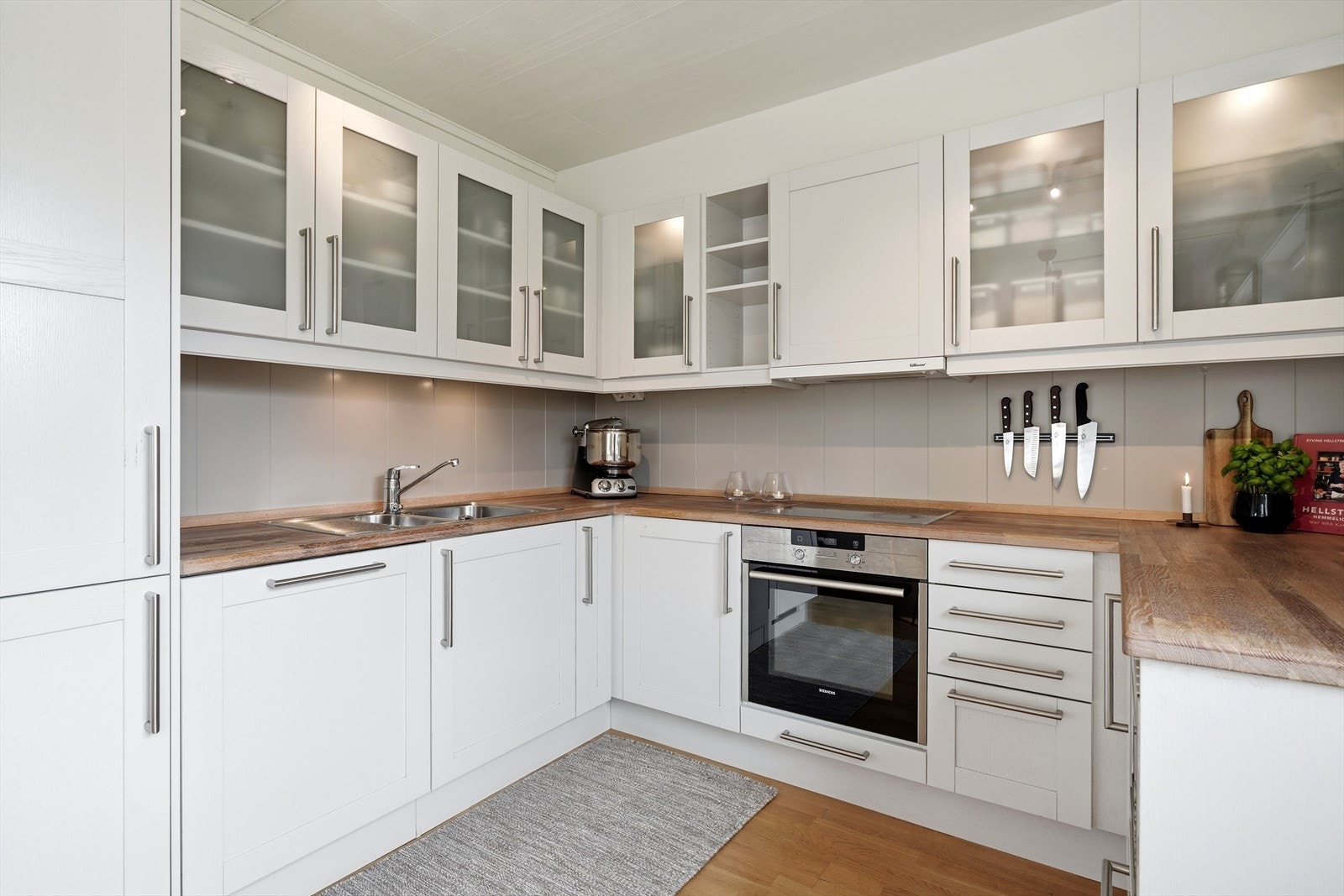 Kjøkkenet har lyse fronter og benkeplate i heltre med nedfelt oppvaskkum og platetopp. Det er integrerte hvitevarer som stekeovn, mikro og kombiskap. Galleribilde