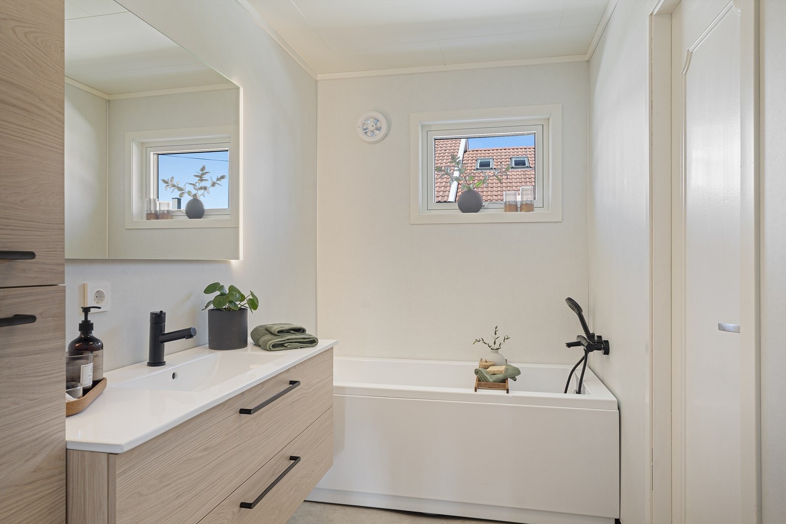 Badet i 1. etasje er renovert i 2026 og fremstår som et moderne og pent våtrom med baderomsplater på vegger, belegg på gulv og elektriske varmekabler Galleribilde
