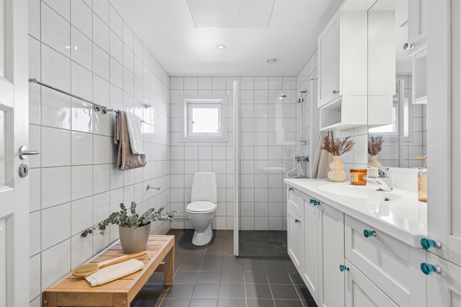 Romslig baderom med tidløse fliser og innredning med mye oppbevaringsplass. Galleribilde