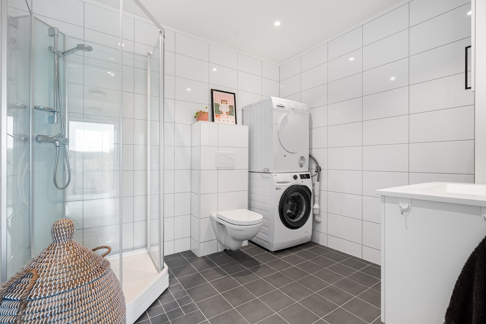 Badet har flislagte vegger og gulv, med elektriske varmekabler. Rommet er innredet med baderomsinnredning med nedfelt servant og praktisk skap- og hylleløsning, speil med integrert belysning, vegghengt toalett og dusjkabinett. Galleribilde