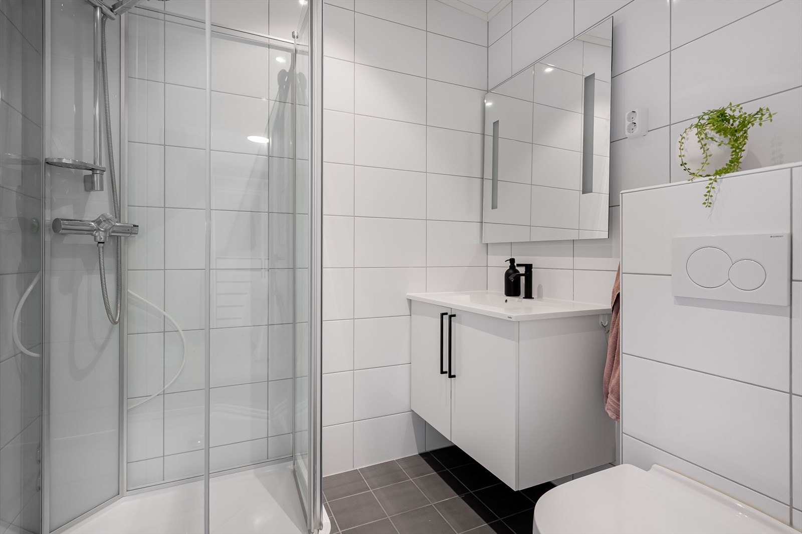 Badet har flislagte vegger og gulv, med elektriske varmekabler. Innredningen består av servant nedfelt i skap med speil over med integrert belysning, vegghengt toalett og dusjkabinett. Galleribilde