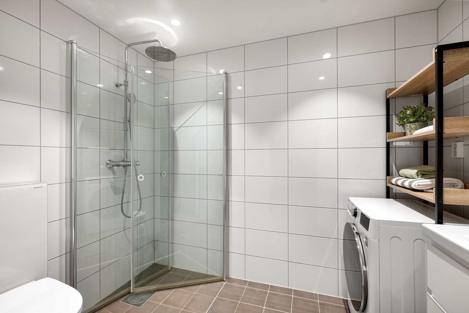 Badet er utstyrt med dusjhjørne med glassdører, toalett og opplegg for vaskemaskin. Galleribilde