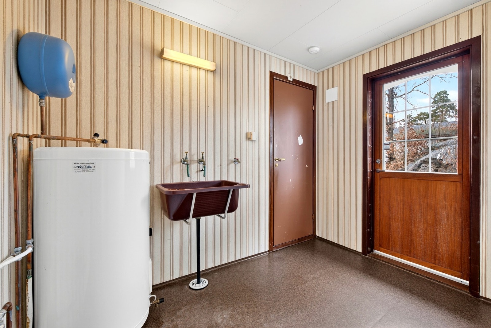 Vaskerom med utslagsvask, varmtvannsbereder, opplegg for vaskemaskin og utgang til uteområdet. Galleribilde