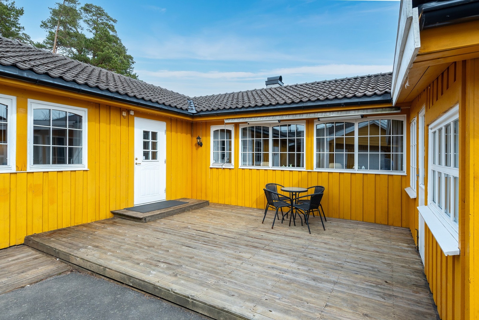Inngangsparti med romslig terrasse. Til venstre er inngangen til boligen, mens man har inngangen til sommerstuen til høyre. Galleribilde