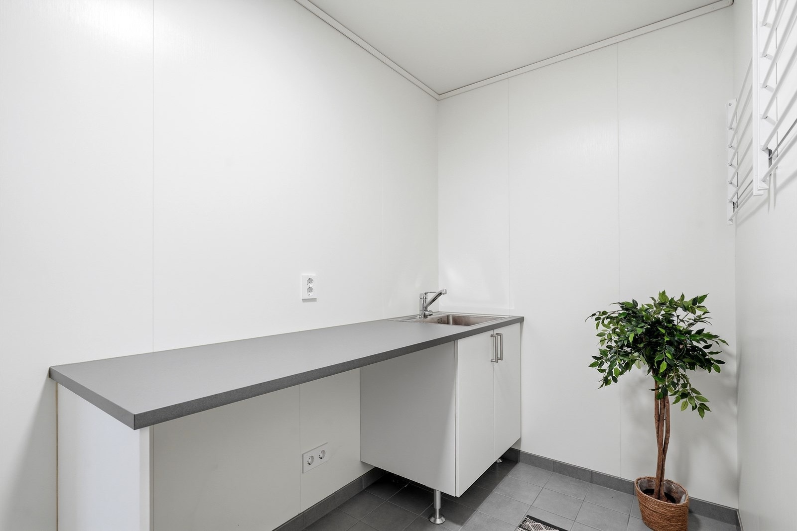 Eget vaskerom med plass til vaskemaskin og tørketrommel under benk. Praktisk innredning med nedfelt stålkum. Galleribilde