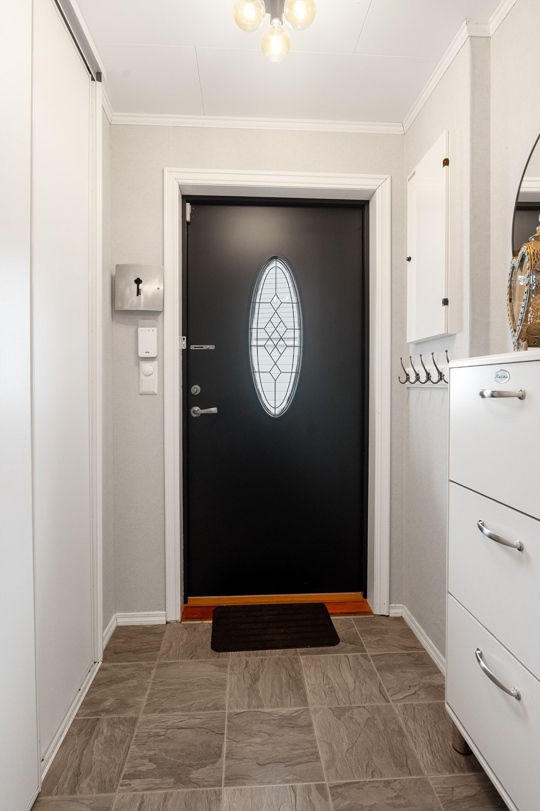Et pent vindfang ønsker deg velkommen inn i boligen - her finner du en romslig skyvedørsgarderobe med plass til sko og yttertøy Galleribilde