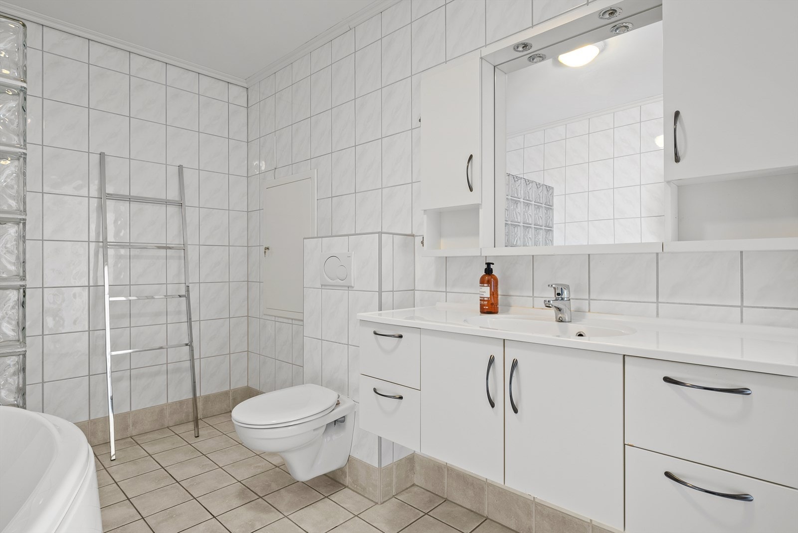 Romslig bad utstyrt med badekar, dusjkabinett, vegghengt wc, innredning, utslagsvask og opplegg for vaskemskin. Galleribilde