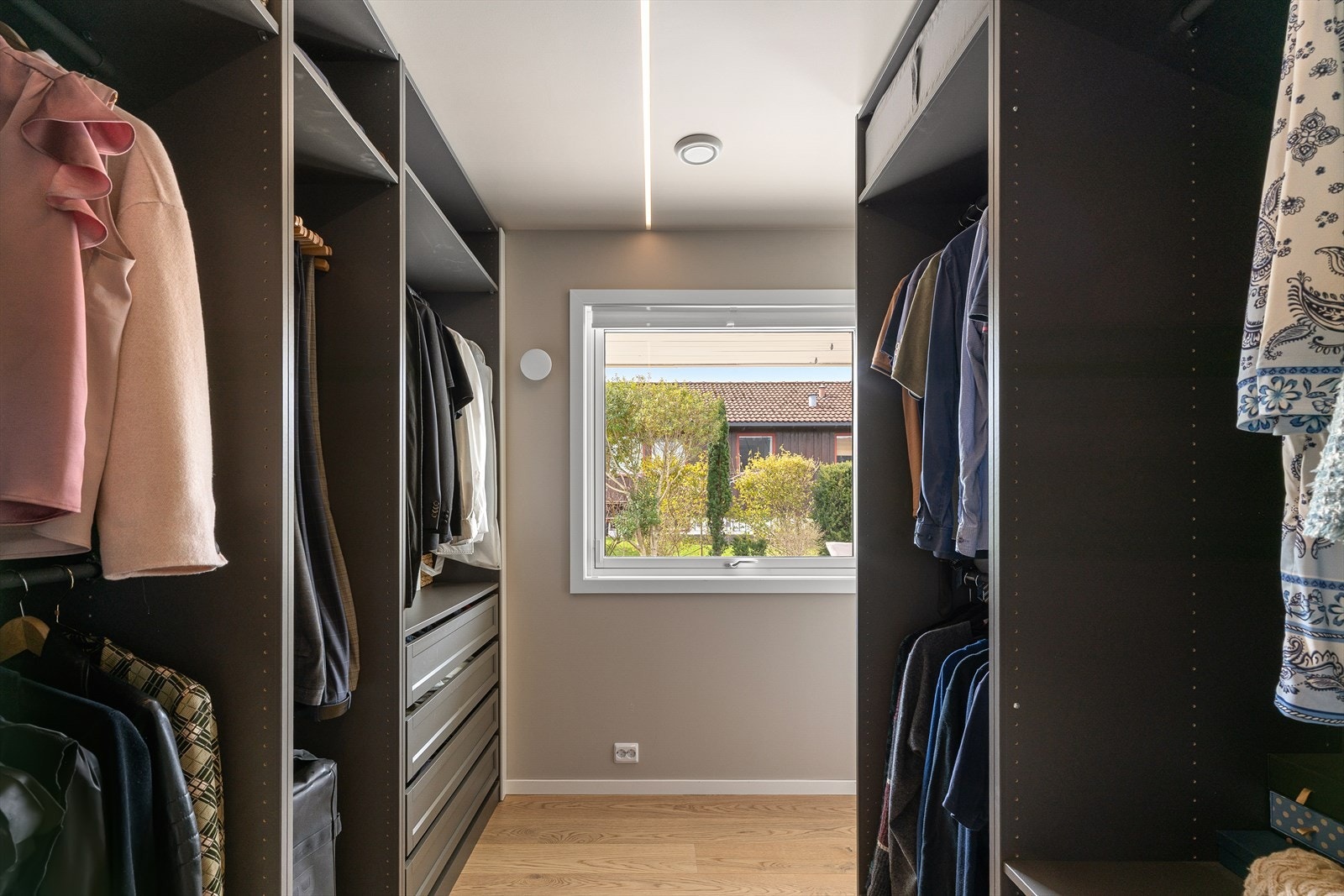Romslig walk-in garderobe med gode oppbevaringsløsninger og naturlig lys. Galleribilde