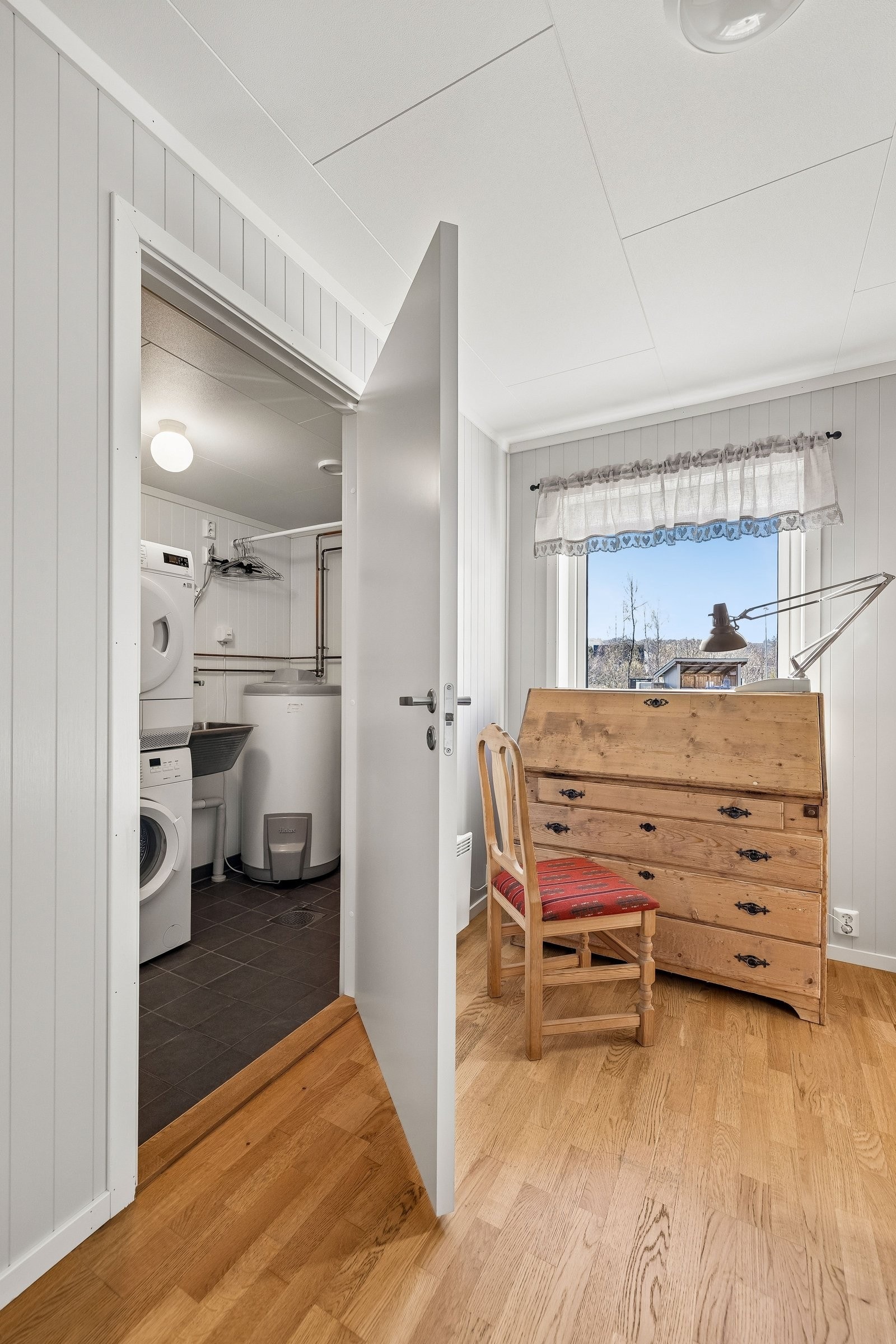 Soverom med dør inn til teknisk rom/vaskerom med vaskekum, varmtvannsbeholder og skap for styring av balansert varmegjenvinning. Galleribilde