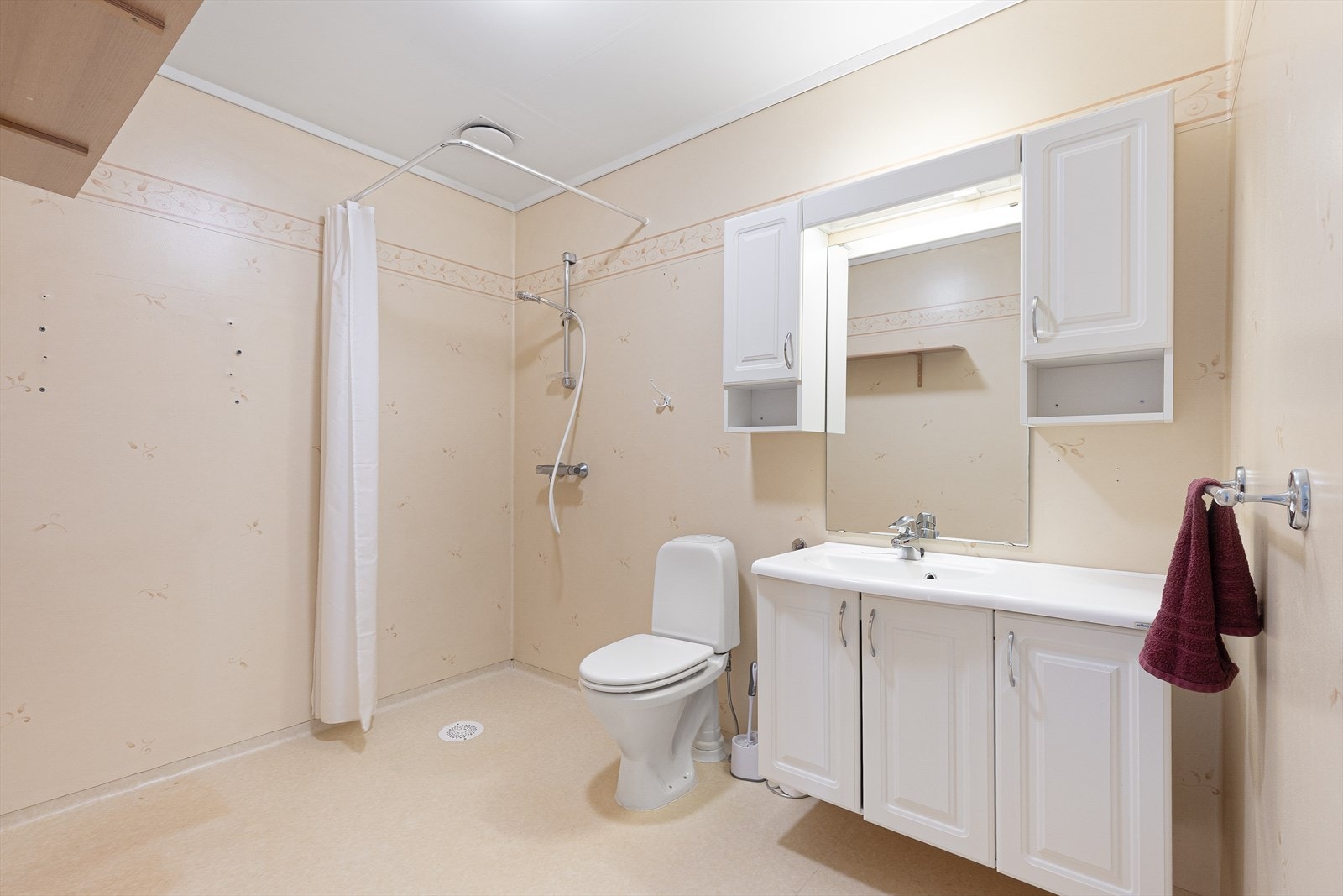 Badet har også dusjhjørne med dusj på vegg, toalett og opplegg for vaskemaskin. På veggoverflatene er det baderomstapet. Rommet har kun naturlig ventilasjon. Galleribilde