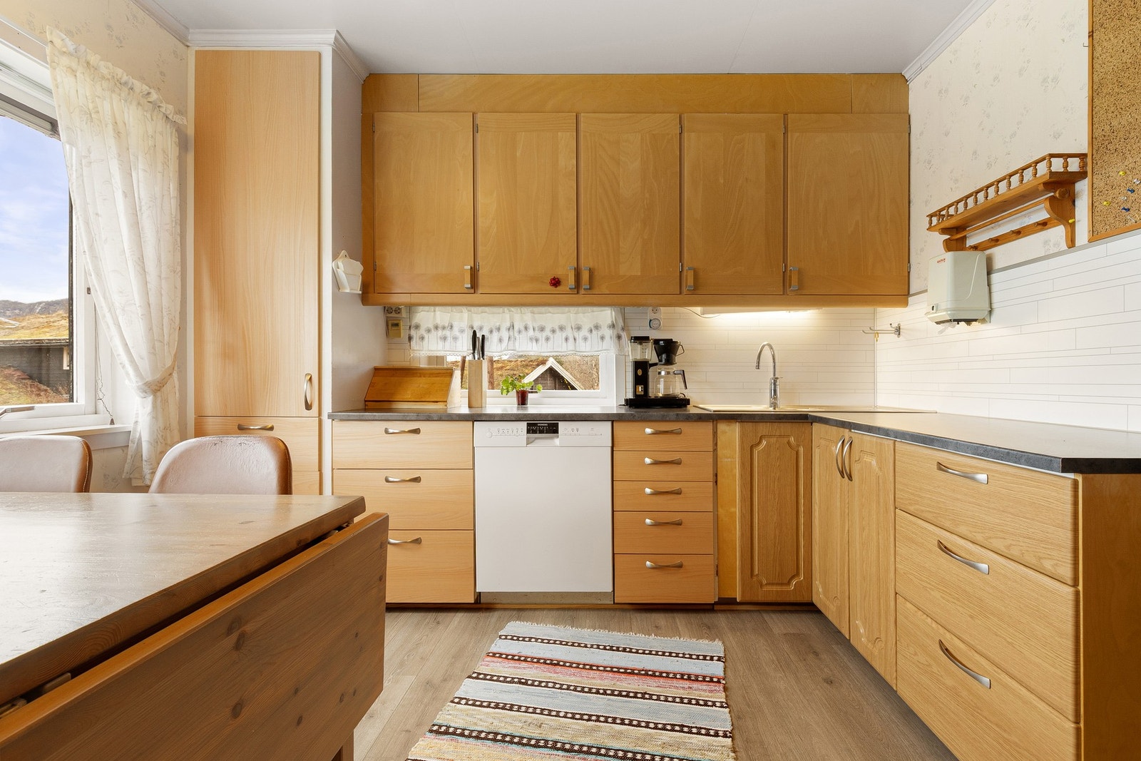 Kjøkkenet har godt med skap- og benkeplass, med kitchenboard - med fliser over kokesone og kitchenboard bak vask. Galleribilde
