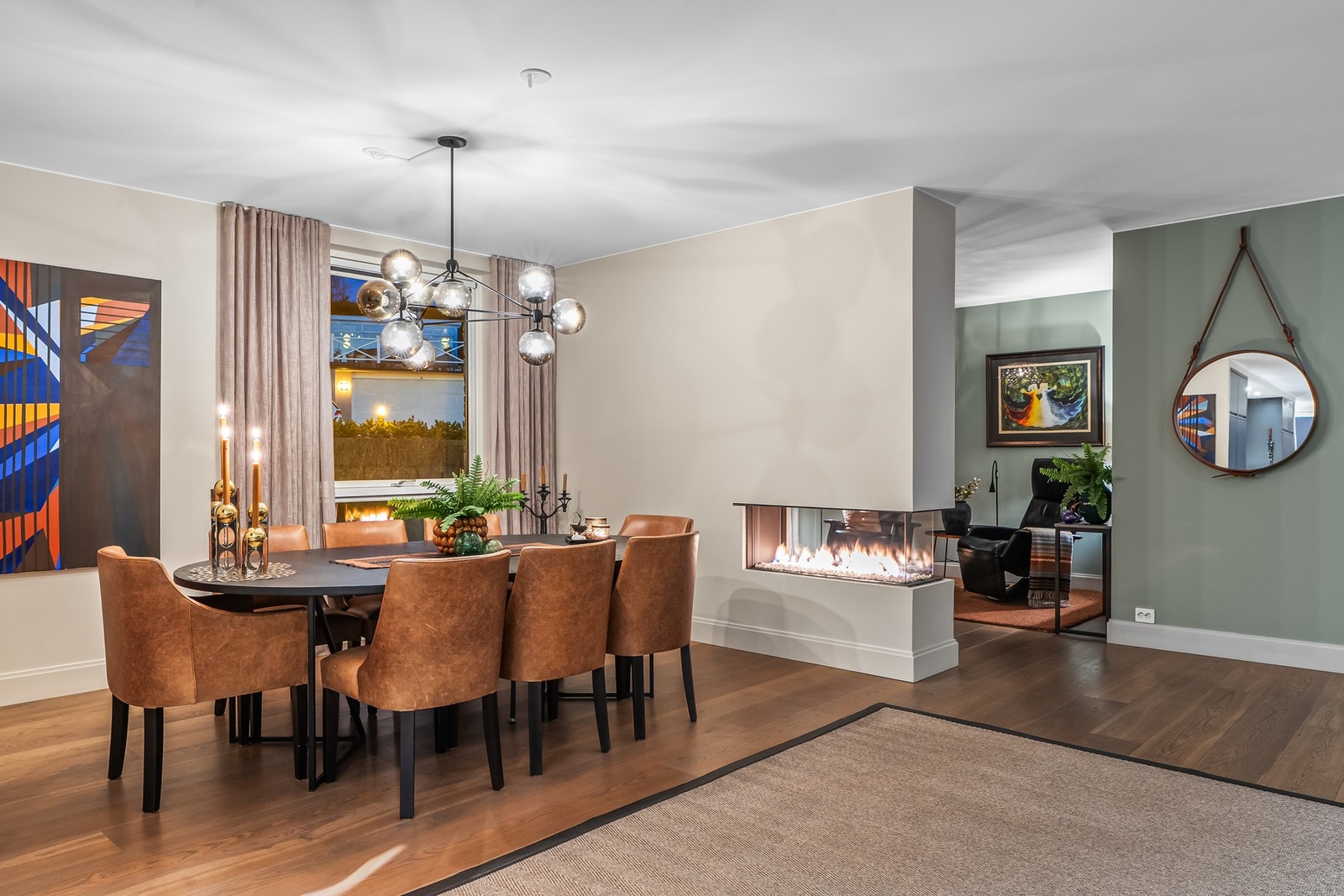Mellom spisestuen og TV-stuen står en gasspeis med innsyn fra begge sider, som både deler rommene på en elegant måte og bidrar til en lun og innbydende stemning. Galleribilde