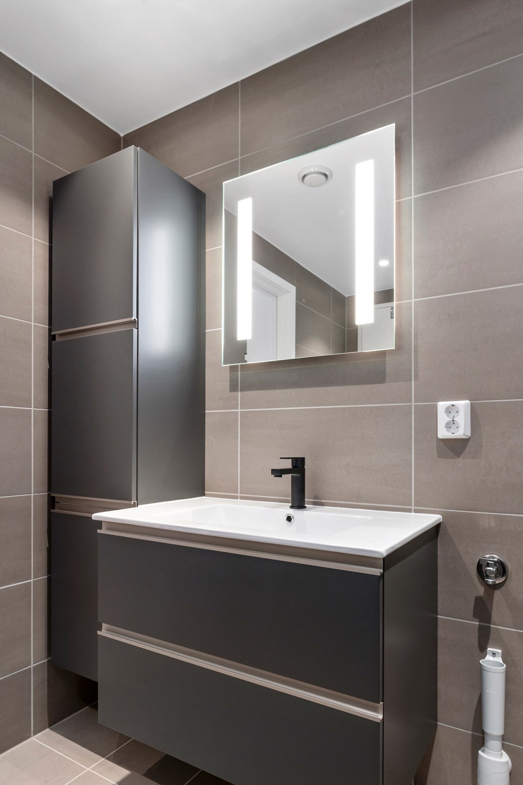 Badet er utstyrt med lekker innredning med mørke glatte fronter. Galleribilde