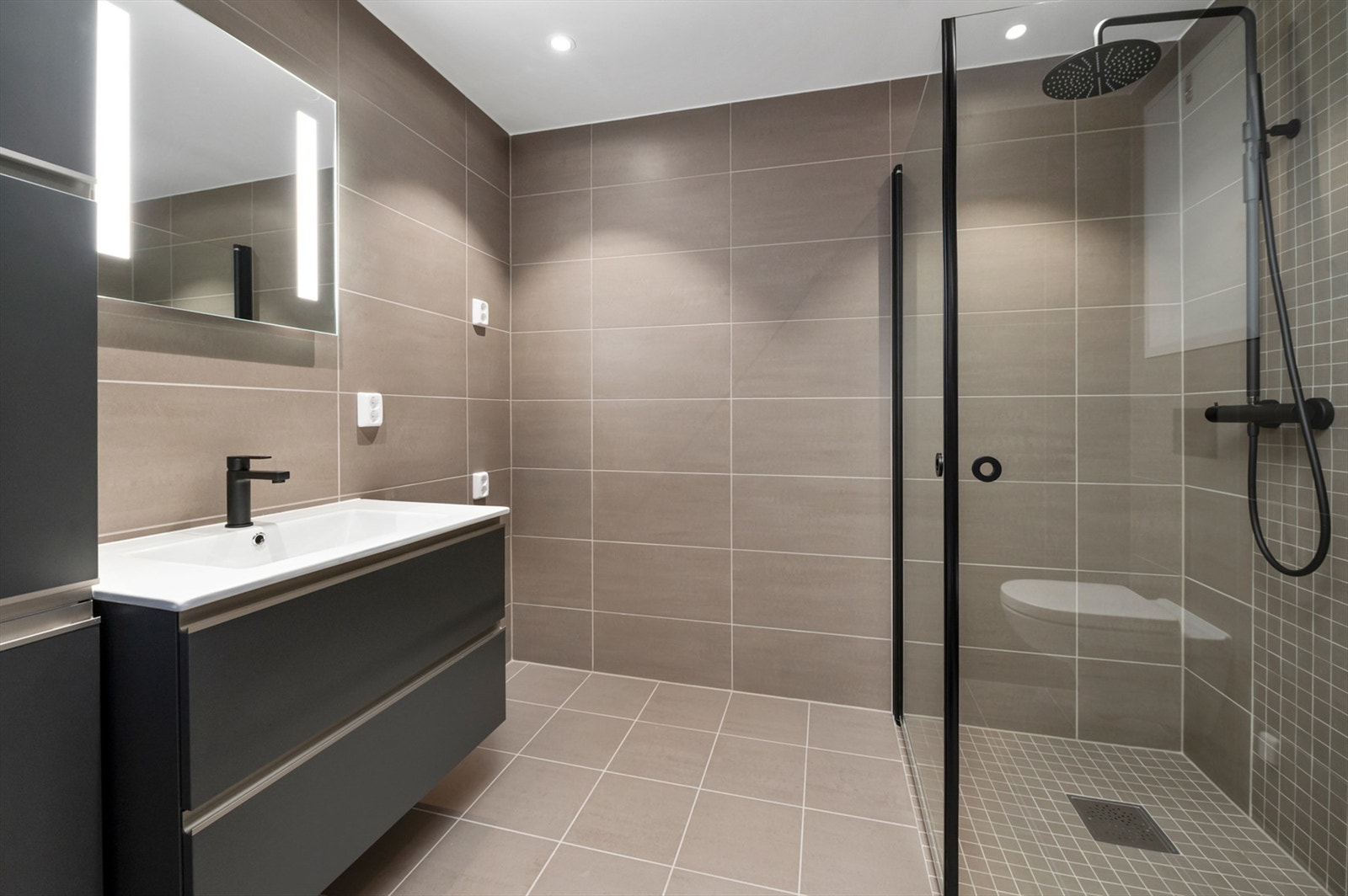 Badet måler 5 kvm og er pent flislagt med varme i gulv, opplegg for vaskemaskin og downlights i himling. Galleribilde