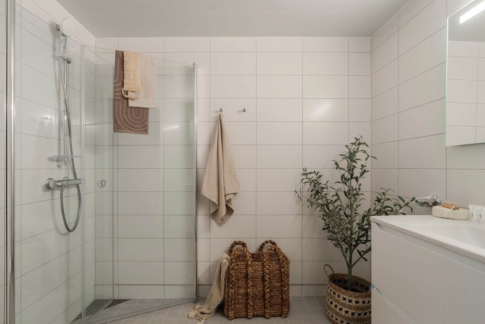Badet er stilrent og moderne, med flislagte overflater og dusj med glassdører. Galleribilde