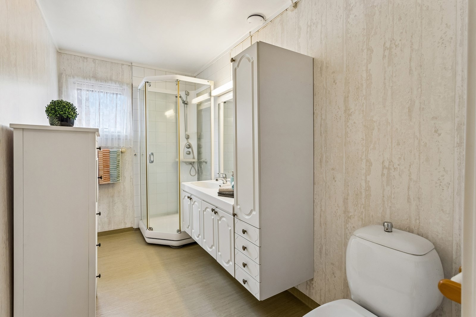 Badet er utstyrt med dusjkabinett, servant med underskap og toalett. Veggene ble oppgradert med tapet i 2016. Galleribilde