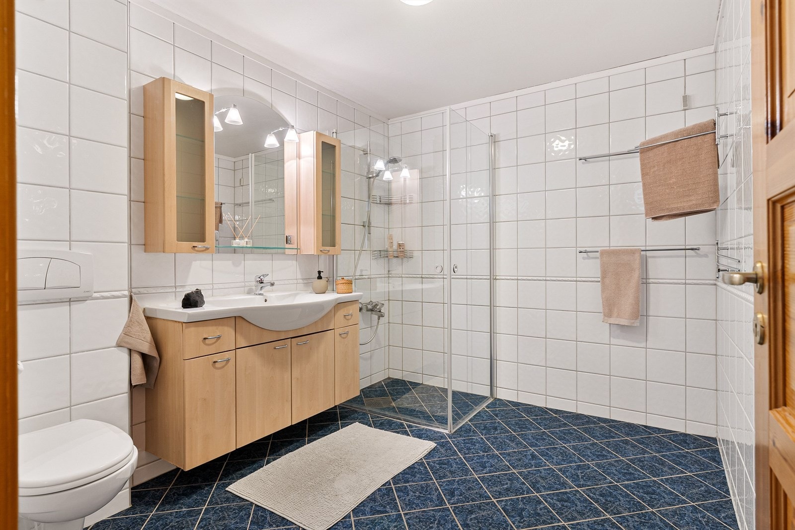 Badet har flislagte overflater og vannbåren gulvvarme. Øvrig innredning består av toalett, dusjnisje og et romlig baderomsmøbel med god plass til baderomsartikler. Galleribilde