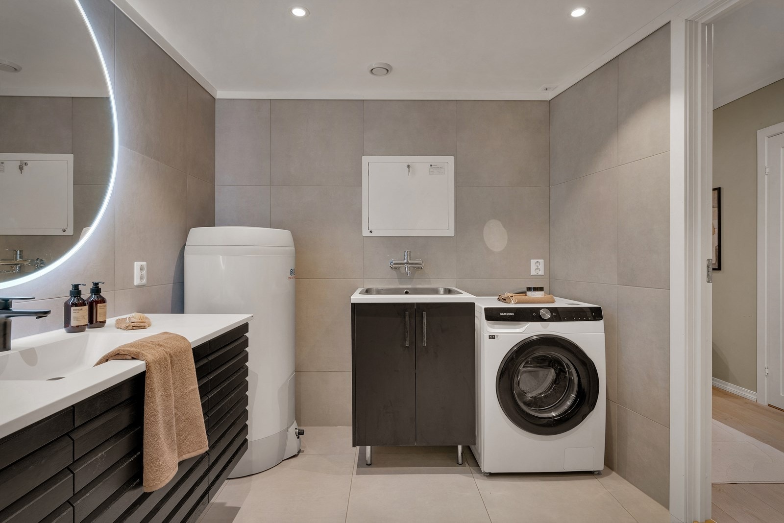 Videre inneholder badet vegghengt toalett, baderomsinnredning fra HTH med servant, stort vegghengt speil med integrert belysning, ny varmtvannsbereder, utslagsvask samt opplegg for vaskemaskin og tørketrommel (med egen stikkontakt). Galleribilde