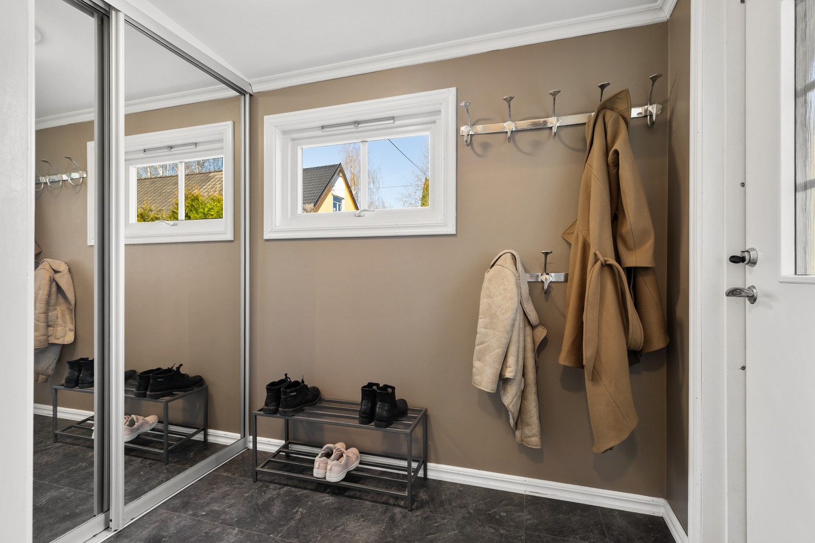 Romslig entré med fin oppbevaringsplass for yttertøy og sko i skyvedørsgarderobe med speilfronter Galleribilde