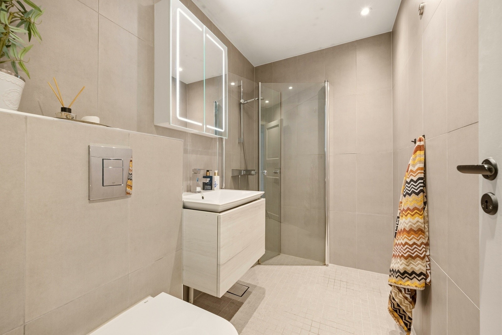 Badet fremstår som lyst og moderne, med flislagte overflater og en praktisk utforming. Galleribilde