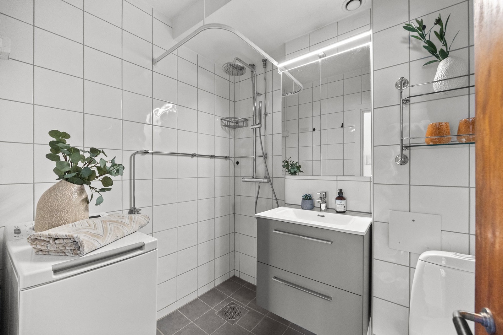 Stilrent bad med oppbevaringsplass under vask og dusjløsning med regndusj. Galleribilde