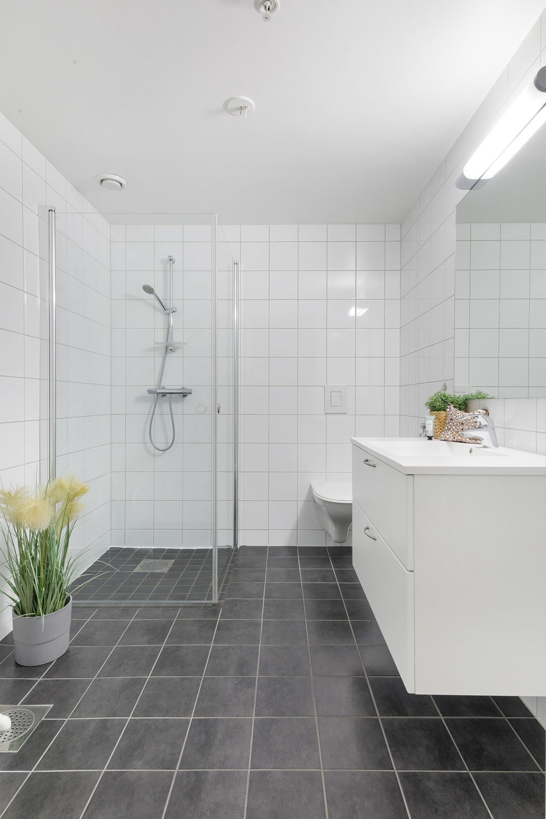 Bad/vaskerom - badet inneholder dusj, vegghengt toalett, servant med speil og opplegg til vaskemaskin og tørketrommel. Galleribilde