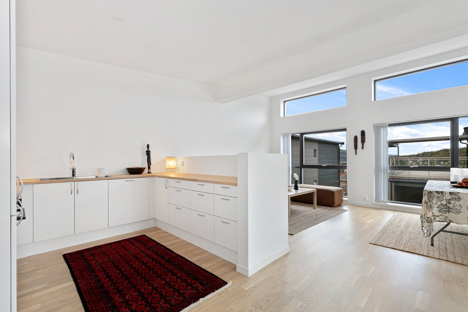 Lyst, moderne kjøkken med folierte skrog og fronter, og heltre benkeplate med nedfelt oppvaskkum. Galleribilde