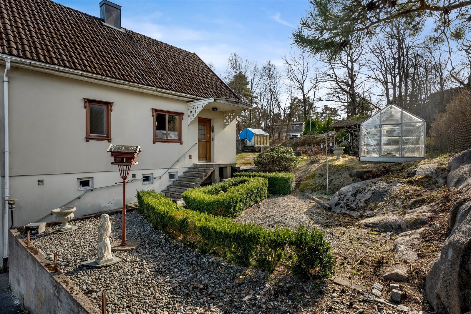 Tomten er opparbeidet med grusganger og prydbusker. Galleribilde