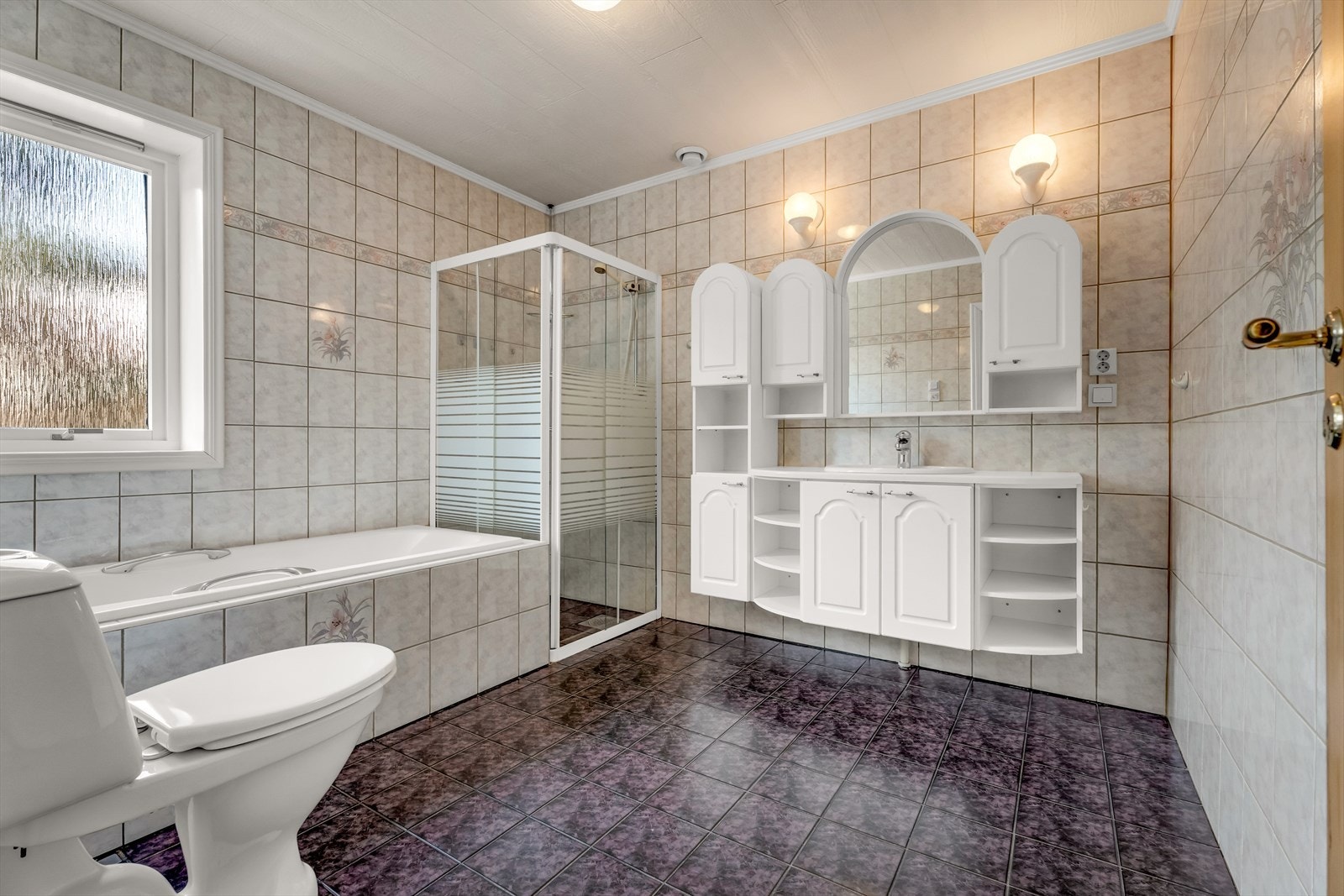 Badet i første etasje er flislagt og utstyrt med både badekar og dusjhjørne med glassdører. Galleribilde