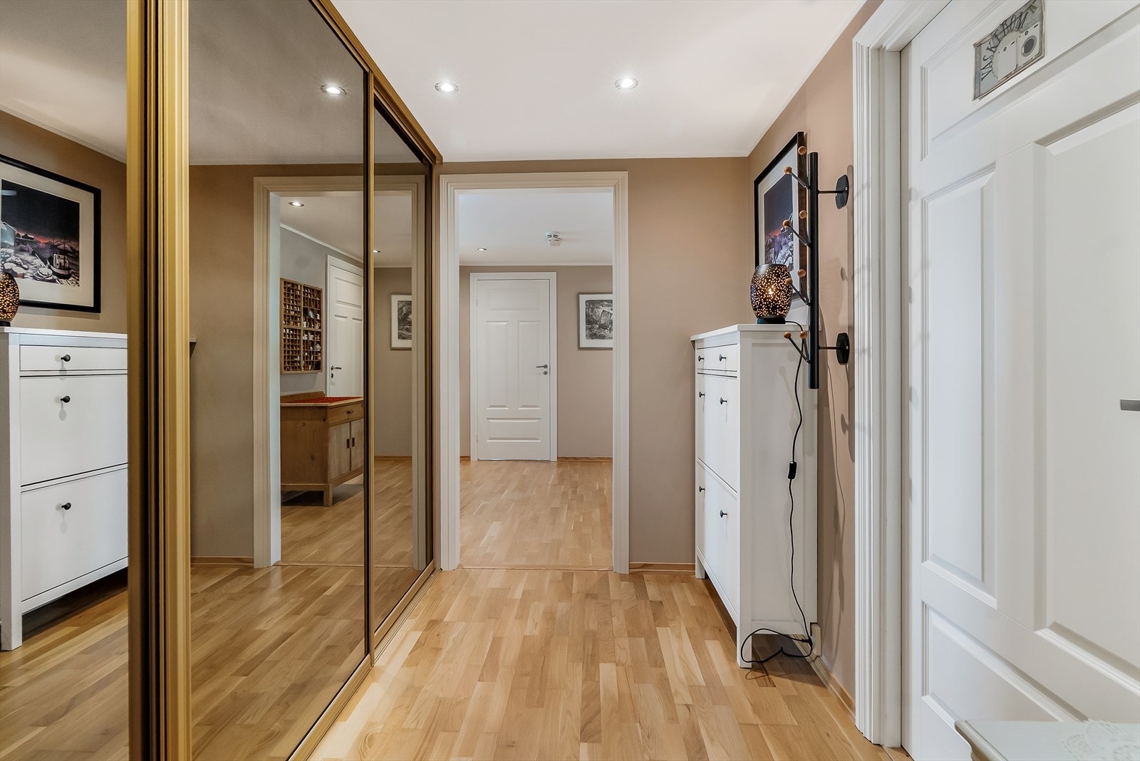 En romslig entré med skyvedørsgarderobe ønsker velkommen og leder videre inn i leiligheten. Galleribilde
